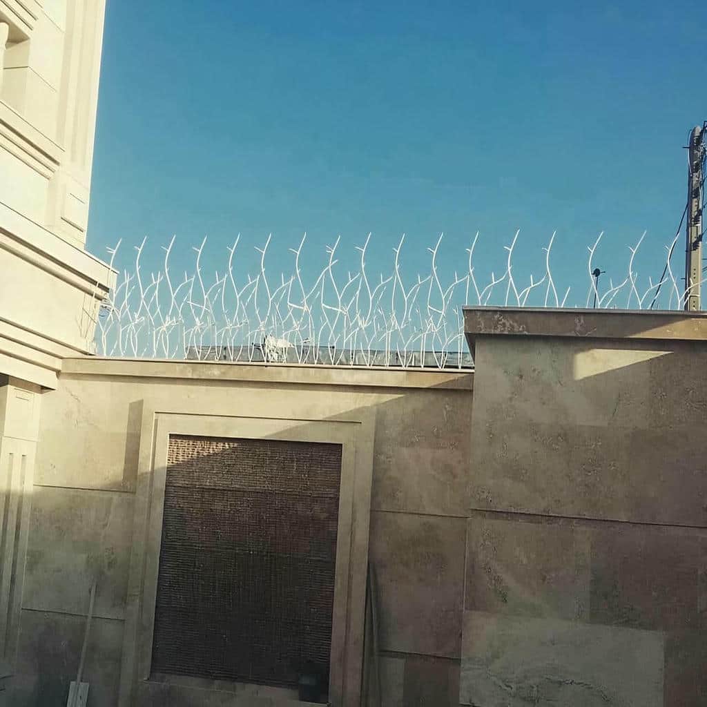 نرده فلزی خاکستری کنار دروازه باغ‌ویلا